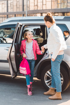 Daughter getting out from car and holding hand of mom