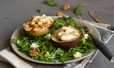 Baked pears with gorgonzola, chicken, walnuts and mozzarella with arugula on a grey plate. Grey slate, stone or concrete table. Healthy salad or snack for Christmas or New Year. Copy space.