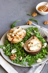 Baked pears with gorgonzola, chicken, walnuts and mozzarella with arugula on a grey plate. Grey slate, stone or concrete table. Healthy salad or snack for Christmas or New Year. Copy space.
