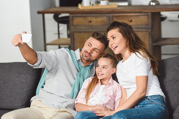 happy family taking selfie on smartphone in living room