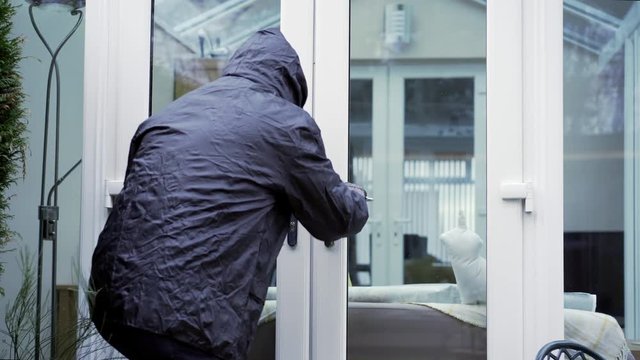 Burglar trying to break into a house by patio doors.