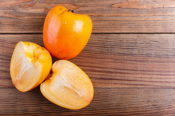 Ripe orange persimmon on brown wooden background