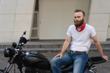 Fototapeta na wymiar Serious brutal motorbike rider waiting for team to start trip. Bearded young man sitting on motorcycle and posing. Riding bike concept