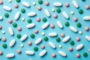 colorful medicine pills, capsules, tablets on blue background, medical pattern, top view, flat lay