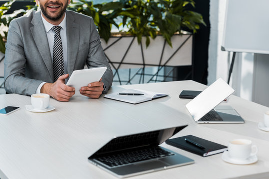 cropped image of businessman holding tablet at table in office