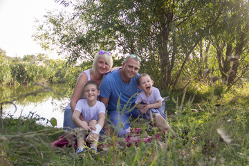 Fototapeta premium Happy parents of two boys relaxing in nature