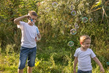 The boy inflates soap bubbles in nature