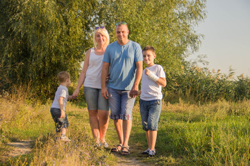 Fototapeta premium Happy parents of two boys relaxing in nature