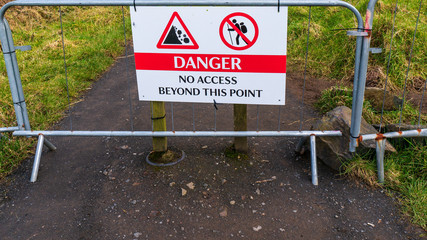 Road closed with danger sign for falling rocks. Forbidden access for hiking.