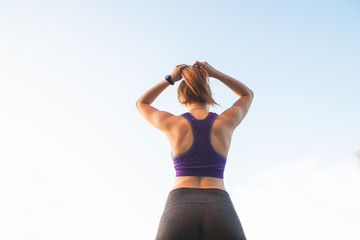 Back fitness girl who tied the tail to the background of the sky. Sports concept.