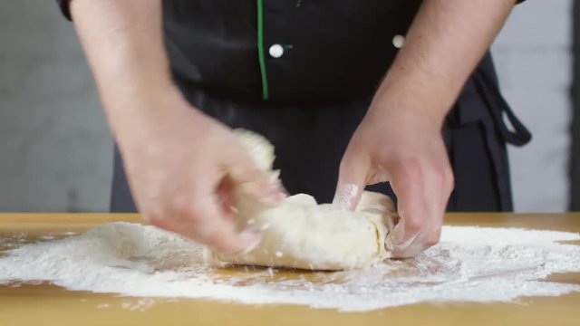 Mid-section shot of hands of unrecognizable male cook kneading dough