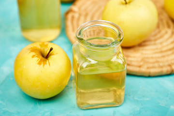 Glass Bottle of apple organic vinegar on blue background.