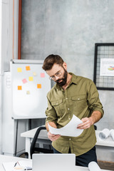 Obraz premium handsome bearded businessman reading documents in office