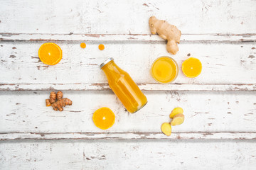 Ginger shot with orange and curcuma on white wood