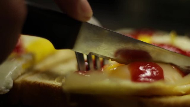 Close up of fried eggs on white bread slice being cut open.
