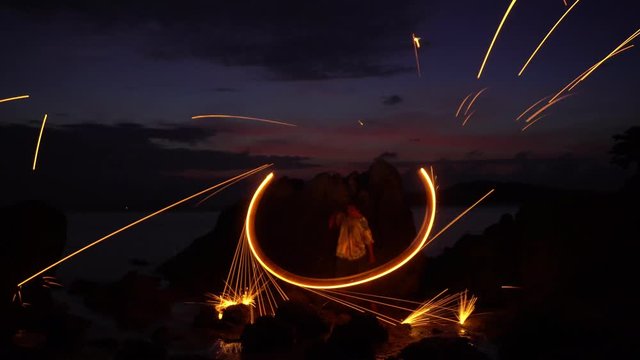 Sparks and fire twirling steel wool with long speed motion in sunset or sunrise time at the tropical sea