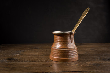 Hot coffee in Turkish copper pot on wooden table