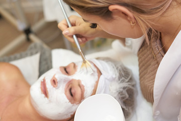 Obraz na płótnie Canvas Cosmetician applying white mask to patient