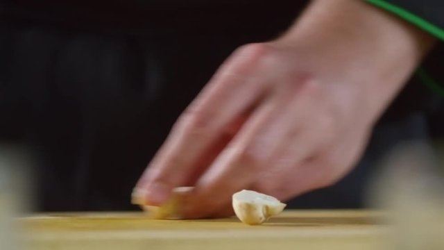 Close up shot of hands of unrecognizable male cook cutting champignon mushrooms with sharp knife