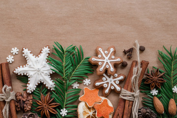 Frame with fir branches, Gingerbread cookies and Christmas decorations on dark brown paper background. Top view.