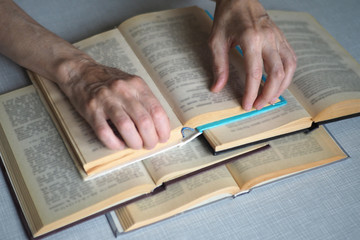 Elderly person hands with opened books, close up, selected focus, blur