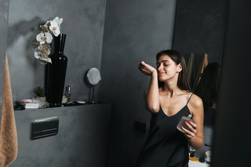 Happy young beautiful woman in bathroom take care of her skin.