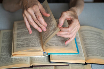 Naklejka premium Elderly person hands with opened books, close up, selected focus, blur