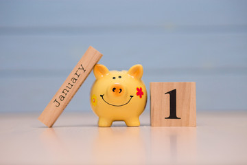 Calendar date of Financial Year start, 1st january with piggy bank on blue background. Winter time.