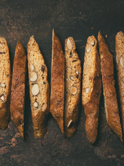 Close View Of Biscotti - Traditional Italian Almond Dessert On Dark Copper Background. Cookies Arranged On The Center In Photo With Copy Space. Top View, Selective Focus, Vertical Composition.