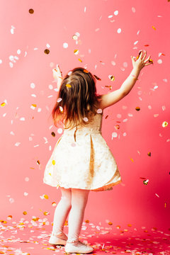 Studio shot of toddler girl throwing confetti