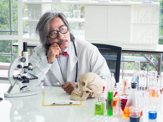 asian doctor looking skull on table