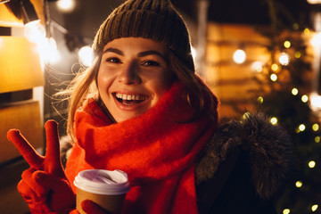 Woman walking outdoors in evening wearing hat and scarf.