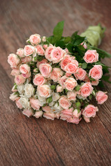 Wedding bouquet of pink and white roses lying on wooden floor