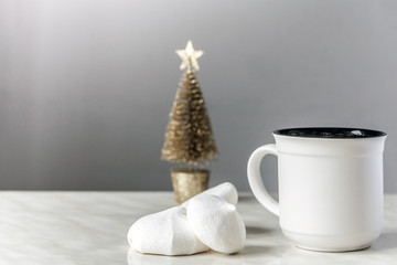Cup of tea, white meringues and golden Christmas tree