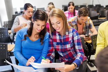 education, high school and people concept - happy student girls with tests at lecture hall