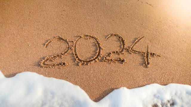 Closeup image of 2024 numbers written on wet sand on the island beach. Concept of New Year, Christmas and travel on winter holidays.