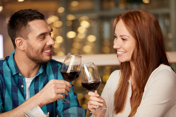 celebration, holidays and people concept - happy couple drinking red wine at restaurant