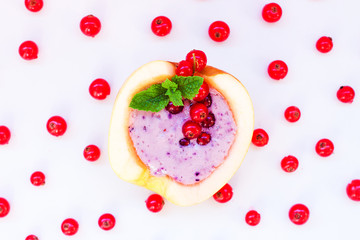 Smoothie in apple with blueberry, banana, mint, red currant and milk on white background. Flat lay. Minimal and modern summer concept.