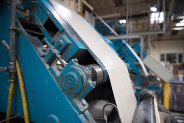 An empty quiet industrial wallpaper and paint factory with giant industrial paint rolling machines, printing white wallpaper.
