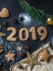 Ginger biscuits of the form of numbers and 2019 new year ginger cookies on dark background. Top view. Seasonal packaging and New Year's attributes