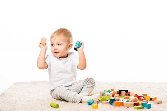 adorable little boy playing with wooden blocks on carpet isolated on white