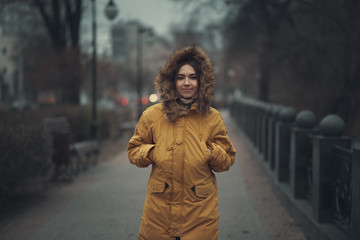 The girl in the yellow jacket in the evening in the autumn city