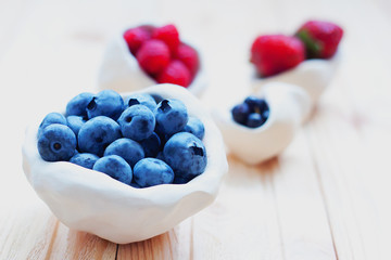 Fresh strawberry, blueberry and raspberry on light wooden background