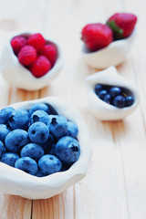 Fresh strawberry, blueberry and raspberry on light wooden background