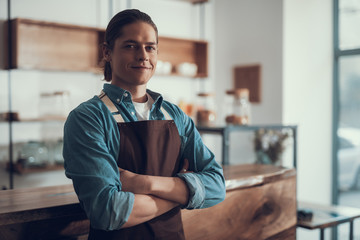 Waist up of confident waiter standing alone and smiling
