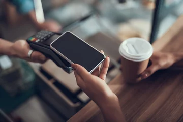 Fotobehang Hand of young lady placing smartphone on credit card payment machine © Yakobchuk Olena