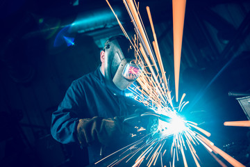 london, england, 02/02/2018 A vibrant action shot of a skilled working metal welder in action, welding metal. Photographed with a slow shutter speed and spark trails. Orange and teal. - obrazy, fototapety, plakaty