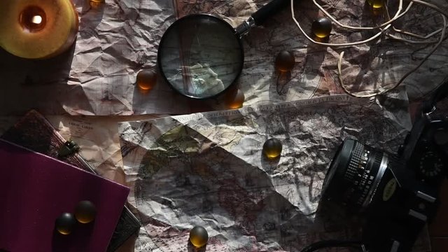 beautiful vintage background with ancient maps, a film camera, a book, a candle some stones and a magnifying glass