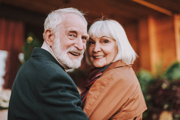 Portrait of joyful bearded man and his wife turning back and smiling. Focus on man