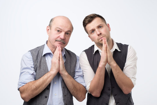 Desperate two men showing clasped hands, asking for help